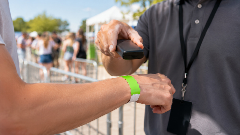 Staff scanning a Tyvek RFID wristband at an event entrance